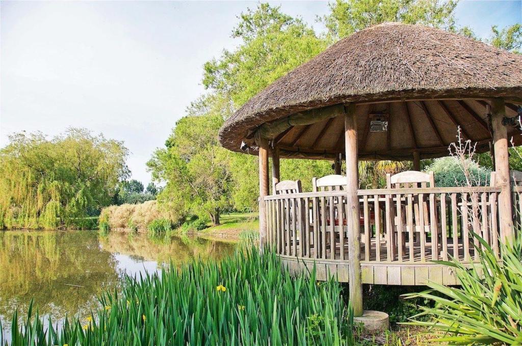a wooden gazebo with chairs and a pond at Northlands Farm Superior Chalet 3 in Chichester