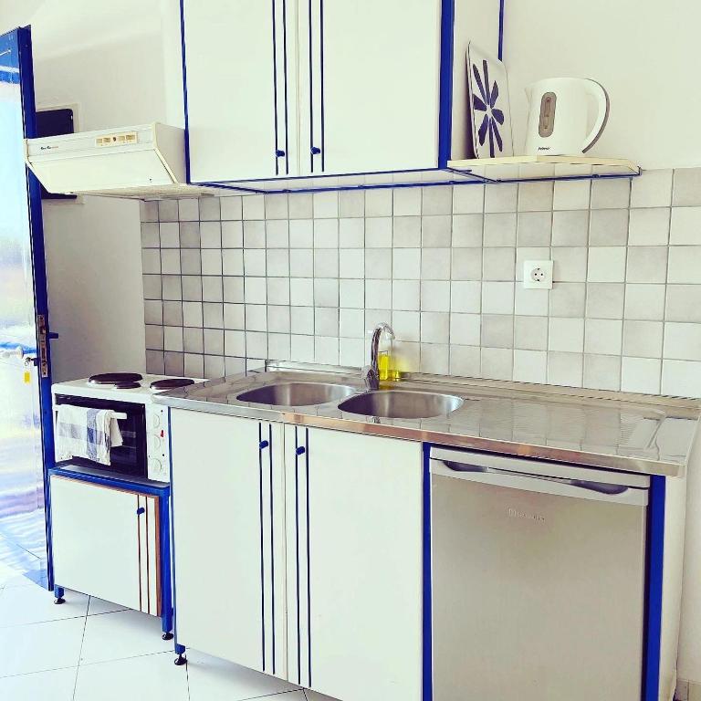 a kitchen with white cabinets and a sink at Spanos Apartments in Agios Petros