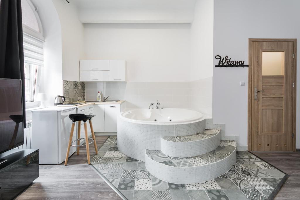 La salle de bains blanche est pourvue d'une baignoire et d'un lavabo. dans l'établissement Jacuzzi JM Rooms Apartment WAWELOFTS, à Cracovie