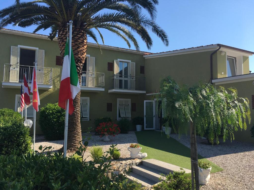 a building with two flags and a palm tree at Hotel Barbarossa in Porto Azzurro