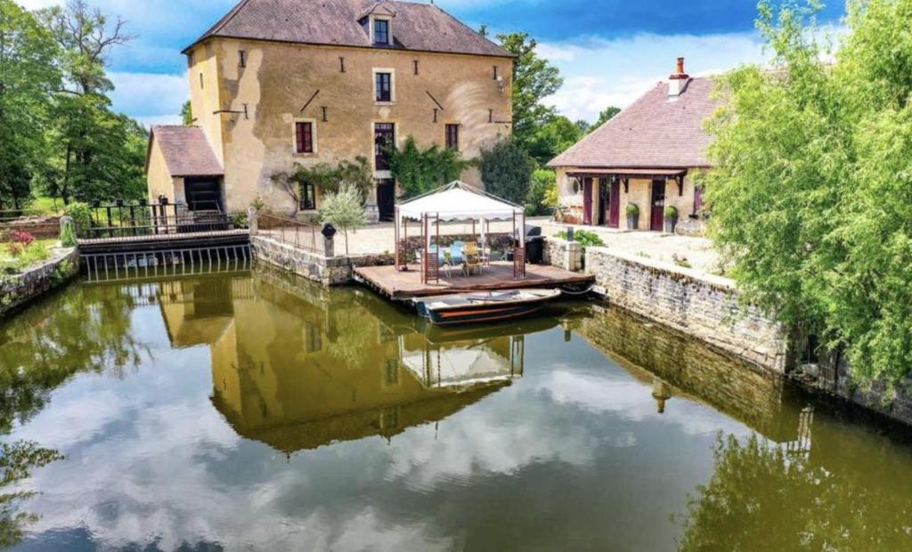 a house on a river with a boat in front at Le Moulin de Gâteau in Saint-Pierre-les-Étieux