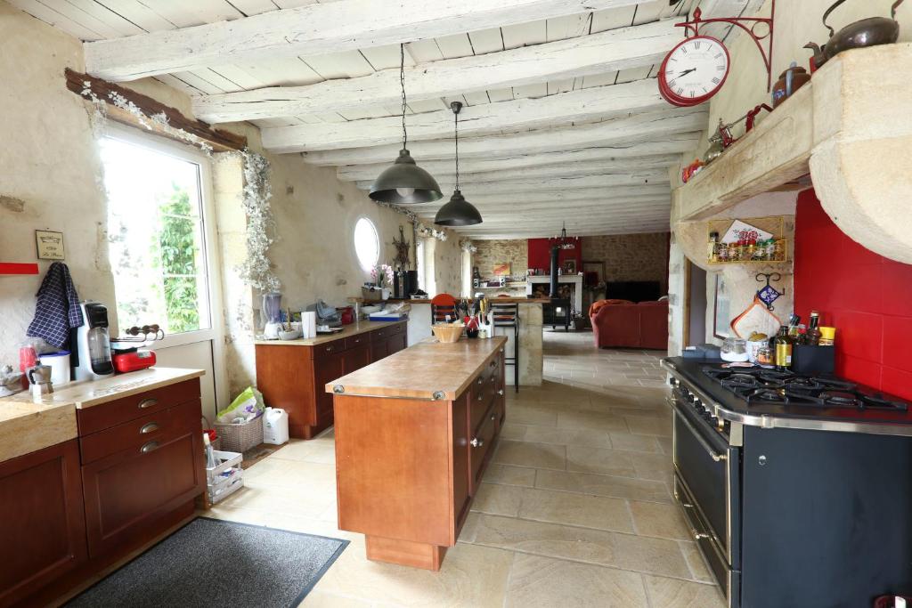 a large kitchen with a counter and a clock on the wall at Le Moulin de Gâteau in Saint-Pierre-les-Étieux