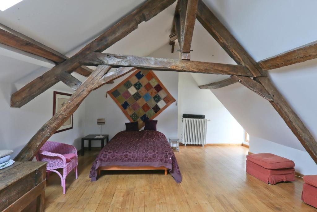 a attic room with a bed and two chairs at Le Moulin de Gâteau in Saint-Pierre-les-Étieux