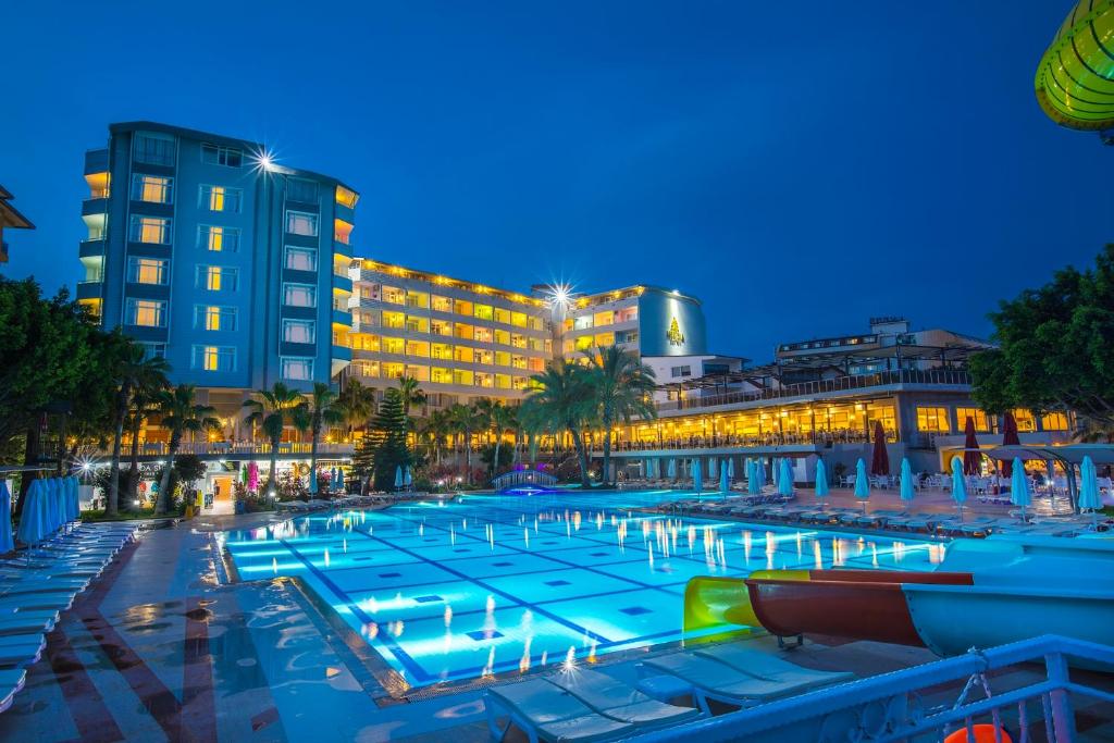 una gran piscina frente a un hotel por la noche en MERİDİA BEACH HOTEL en Okurcalar