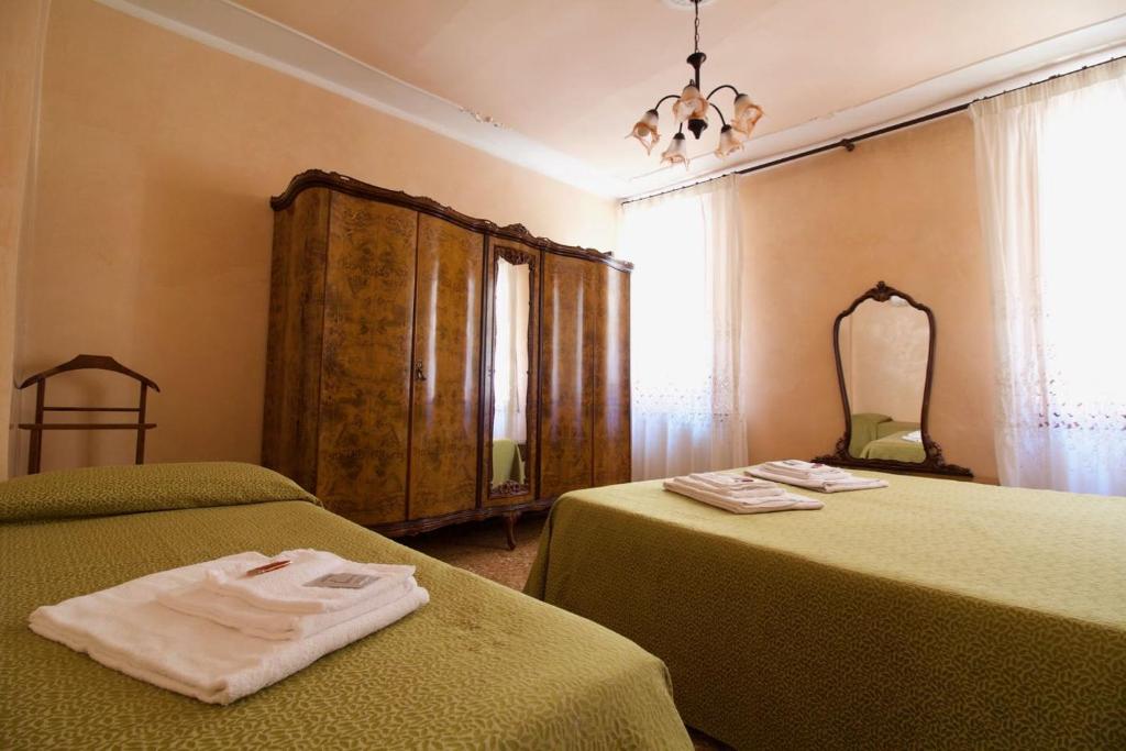 um quarto com 2 camas verdes e um espelho em Veneziacentopercento Arsenale Apartment em Veneza