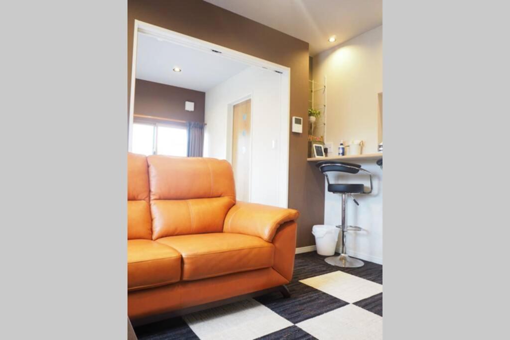 Harbour Inn & Suites 201 في نيغاتا: أريكة برتقالية في غرفة المعيشة مع منضدة