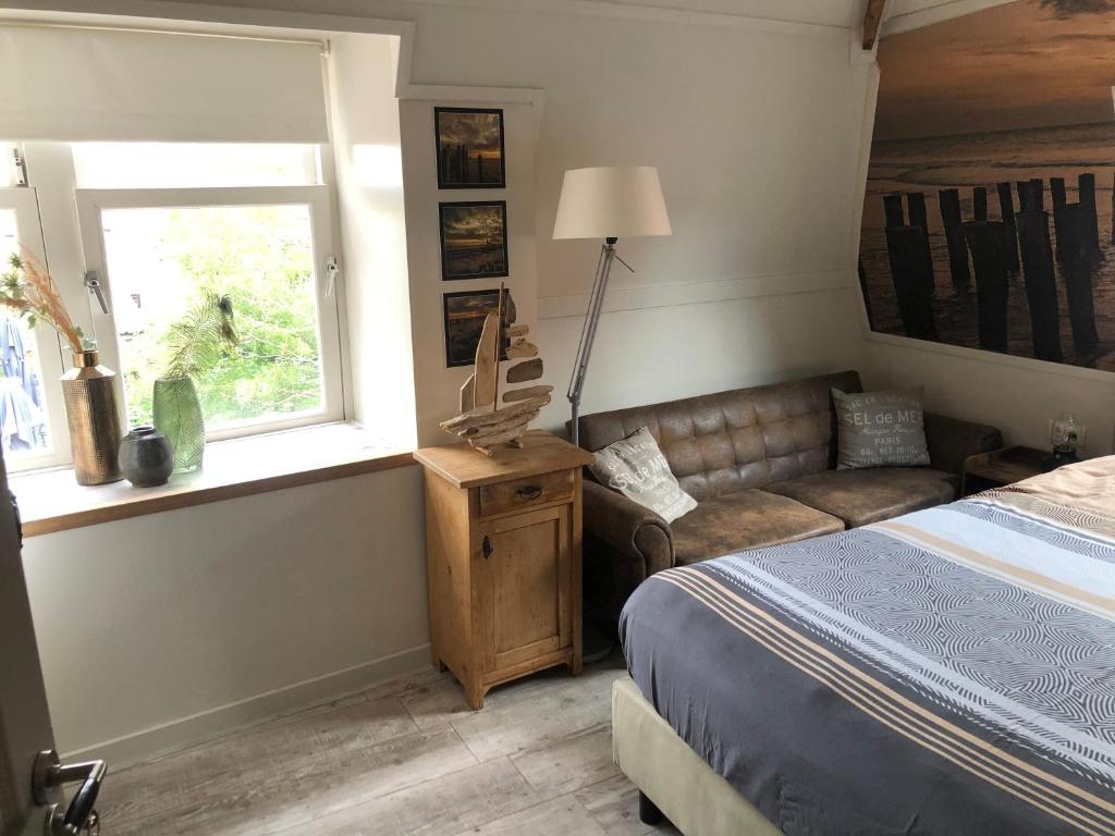 1 dormitorio con cama, sofá y ventana en Brasserie de Peperboom, en Veere