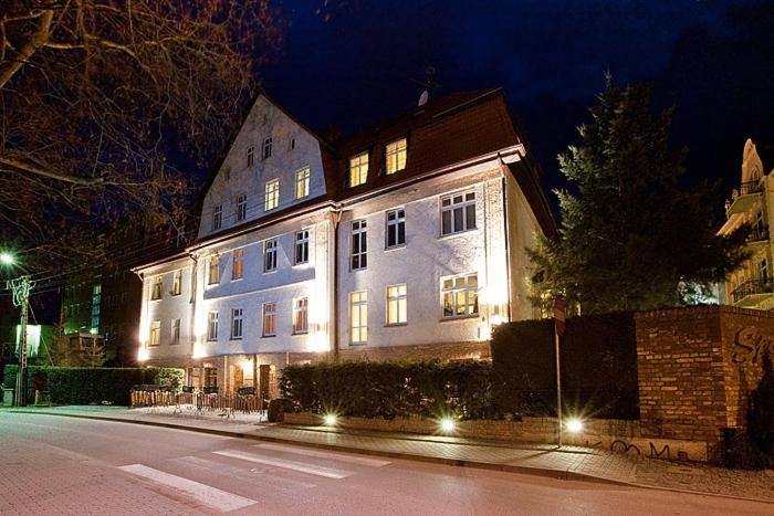 Un gran edificio blanco con luces por la noche. en Kamienica Sporting, en Międzyzdroje