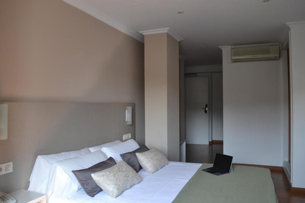 a bedroom with a white bed with a laptop on it at Duerming Villa De Sarria Hotel in Sarria