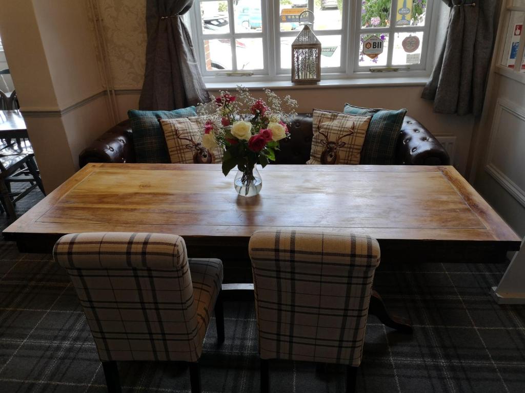 a wooden table with a vase of flowers on it at Woolpack Inn in Chichester