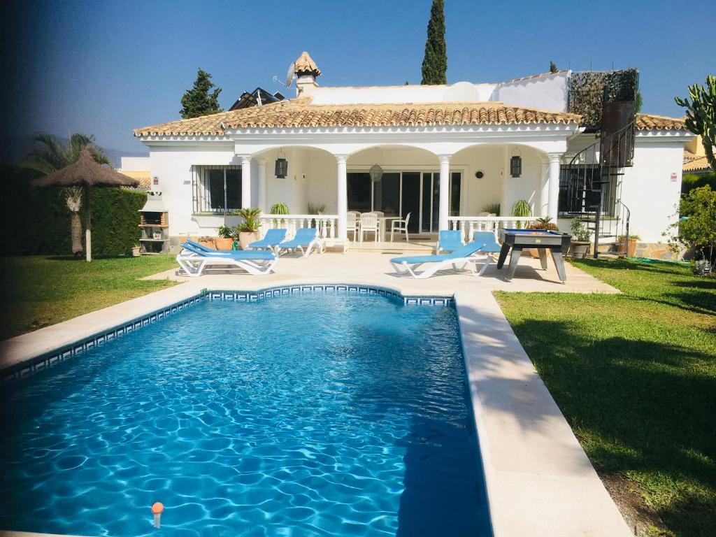 a villa with a swimming pool in front of a house at Villa Pinsapo in Estepona