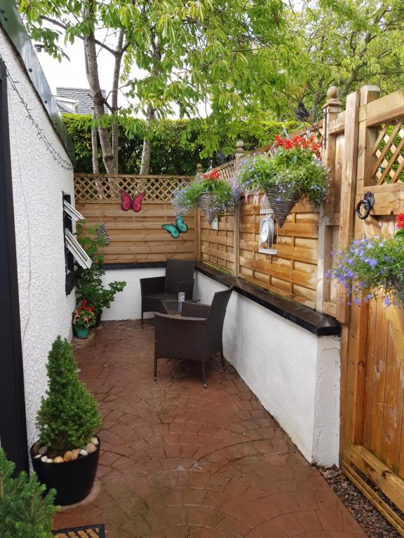 um pátio com uma mesa, cadeiras e plantas em The little garden hoose em Inverness
