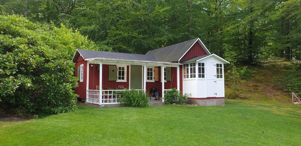 une maison rouge et blanche au milieu d'une cour dans l'établissement Stuga på Hallandsåsen, à Hjärnarp