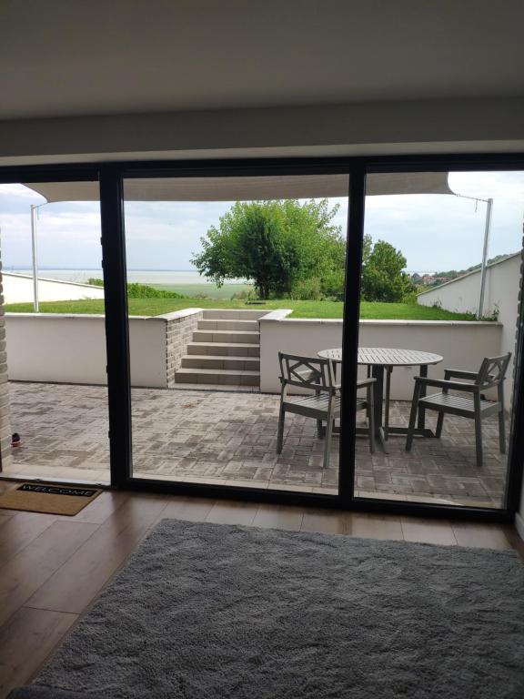 - une vue sur le patio par une porte coulissante en verre dans l'établissement Panorama & Vino apartman, à Szigliget