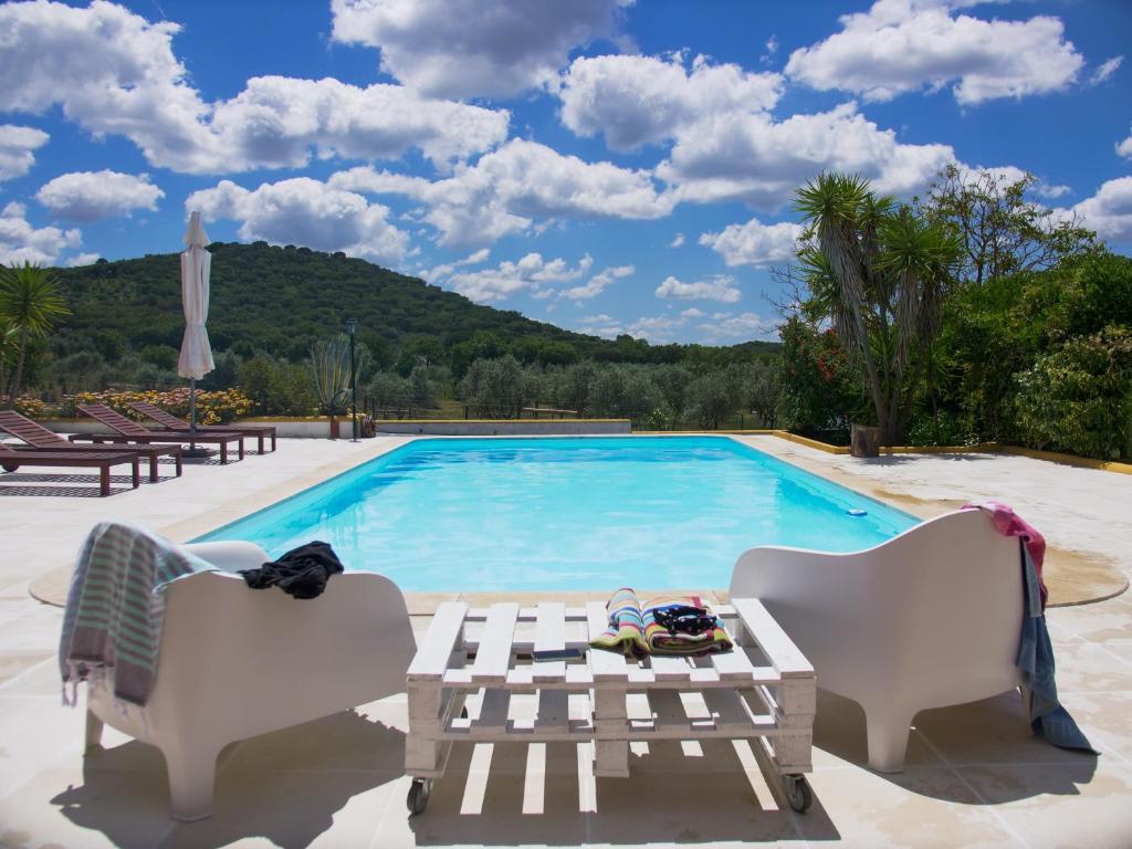 een zwembad met twee stoelen en een tafel ernaast bij Casas de Santa Rita in Évora Monte