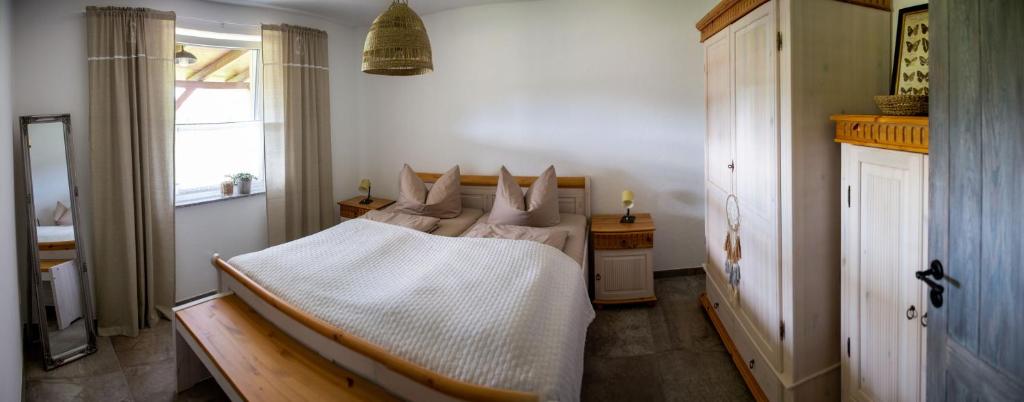 a bedroom with a bed with white sheets and a window at Blumenhuhnhof in Burg Kauper