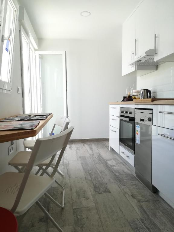 a kitchen with white cabinets and a table and chairs at Apartamento La Zarzuela in Zahara de los Atunes