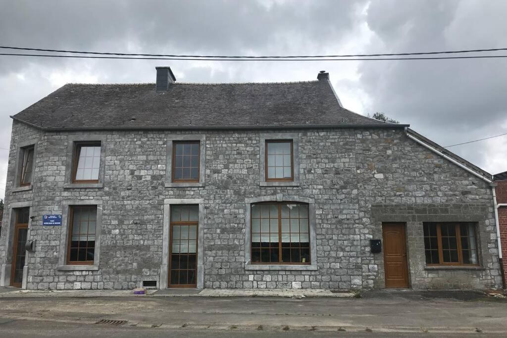 - un vieux bâtiment en pierre avec des fenêtres donnant sur une rue dans l'établissement Petite maison à la campagne, à Couvin