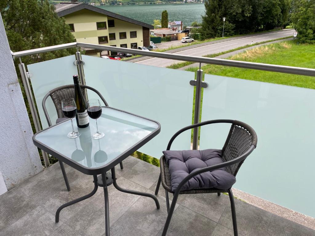 un tavolo di vetro e 2 bicchieri di vino sul balcone di Ossiach Apartment 2 a Heiligen Gestade