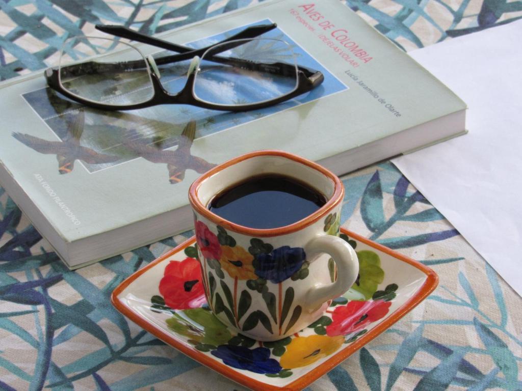 Una taza de café en un plato junto a un libro. en Reserva Guadalajara - Cocora Valley, en Salento