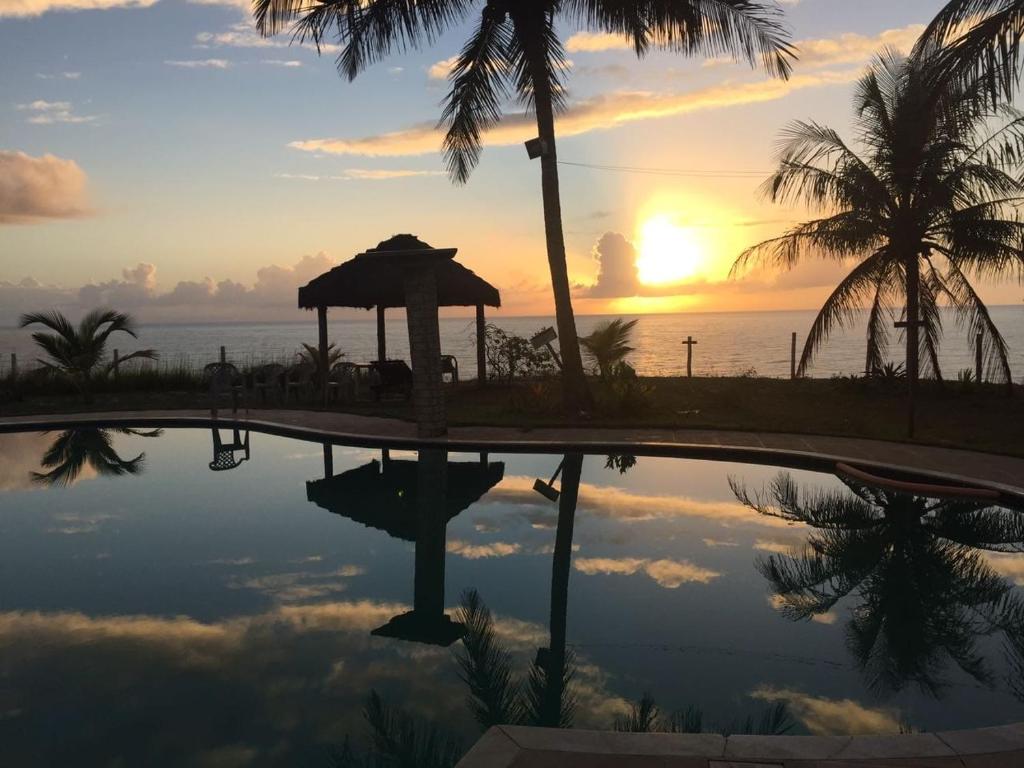 einen Pool mit Sonnenuntergang im Hintergrund in der Unterkunft HOTEL PRAIA DA PAIXÃO in Prado