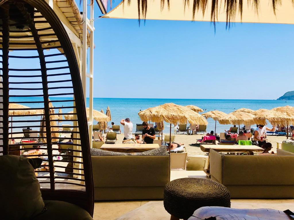 una spiaggia con tavoli e ombrelloni di paglia e l'oceano di Cubaneros Holiday Inn a Laganas