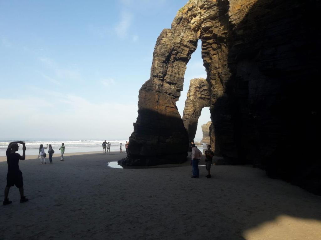 a group of people standing on a beach near the ocean at Apartamentos Turísticos Rosa in Ribadeo