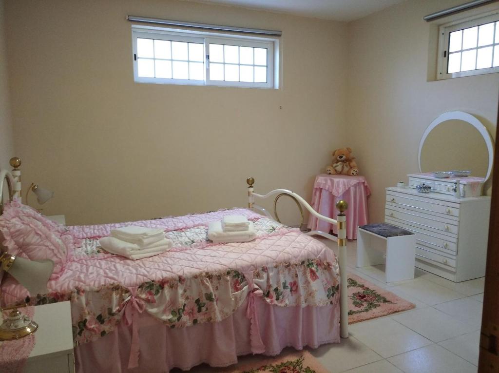 a bedroom with a pink bed with a dresser and a mirror at Casa do Cascão in Louredo