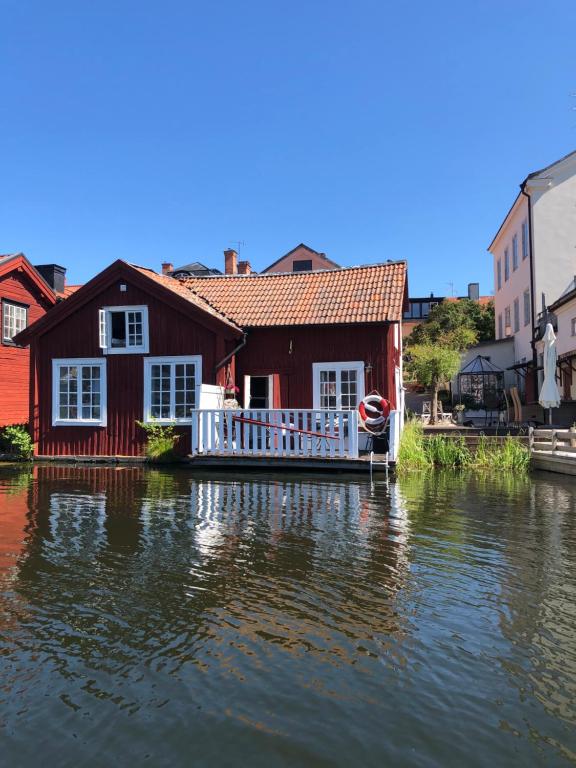 ein Haus auf dem Wasser mit einem Boot davor in der Unterkunft Stugan med Bryggan i Gamla Staden in Eskilstuna