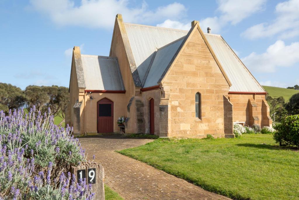 una iglesia con flores púrpuras delante de ella en St. Peter's Accommodation Cape Bridgewater en Cape Bridgewater