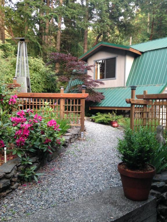 a garden with a bench and flowers and a house at Salt Spring Carriage House B&B in Ganges