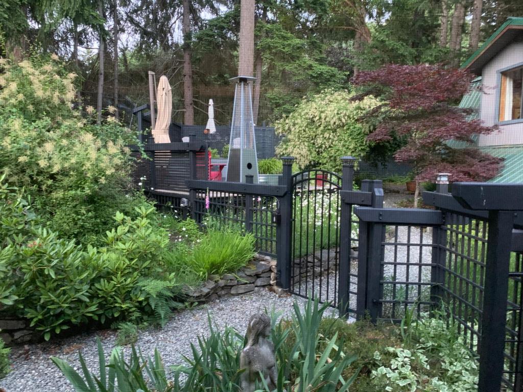 a black fence in a garden with a cemetery at Salt Spring Carriage House B&B in Ganges