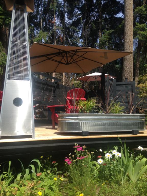 a patio with a table and an umbrella and flowers at Salt Spring Carriage House B&B in Ganges