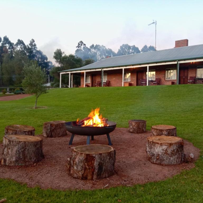 a fire pit surrounded by logs in front of a building at Blackwood Valley Suites in Balingup