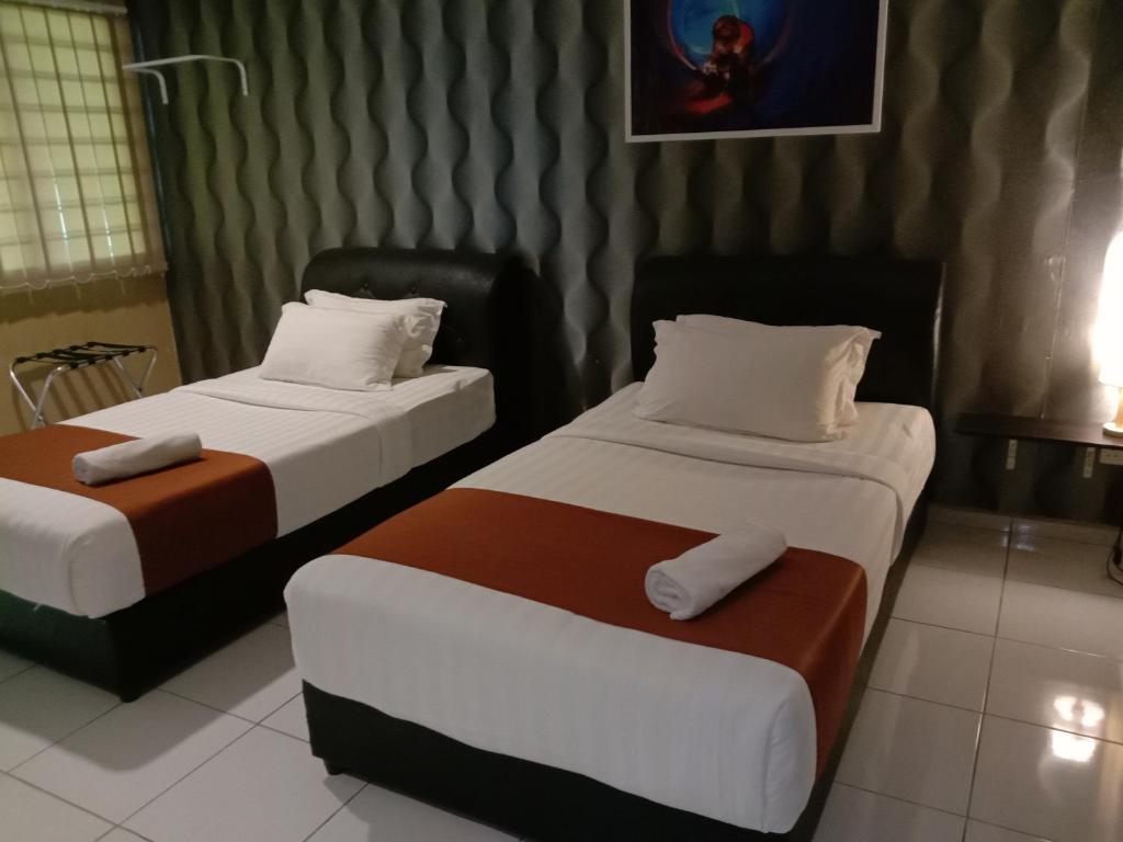 two beds in a hotel room with two bedsitures at NDE Hotel in Dungun