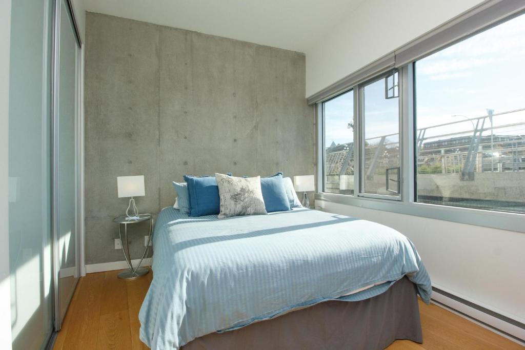 a bedroom with a bed and a large window at Historic Waterside With Spectacular Johnson Bridge Views in Victoria