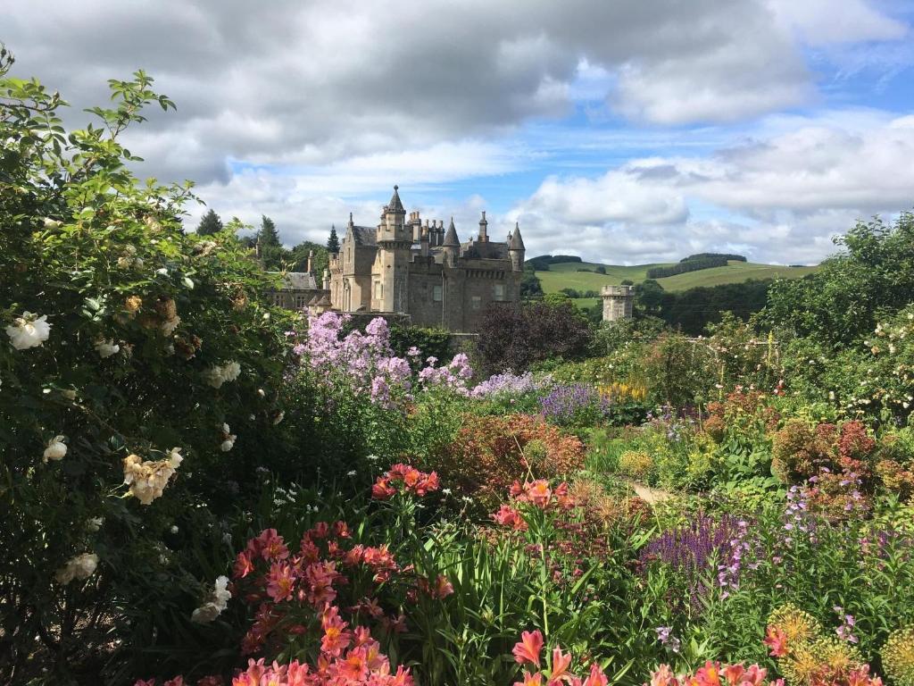 a castle in the middle of a garden with flowers at Tweedbank in Galashiels