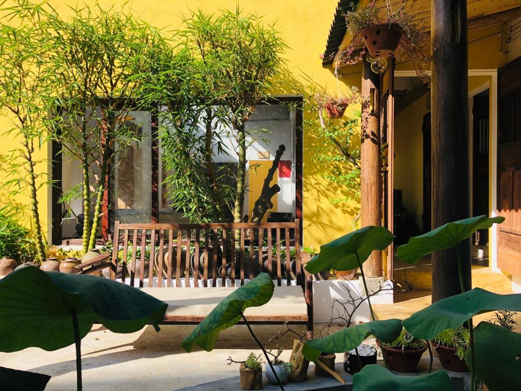 un edificio amarillo con un banco y algunas plantas en Leranda Homestay, en Hue