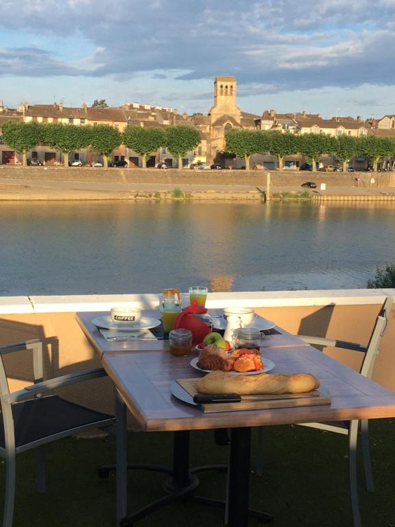 un tavolo con del cibo sopra, accanto a un corpo d'acqua di Domaine les jardins de la Saône a Tournus