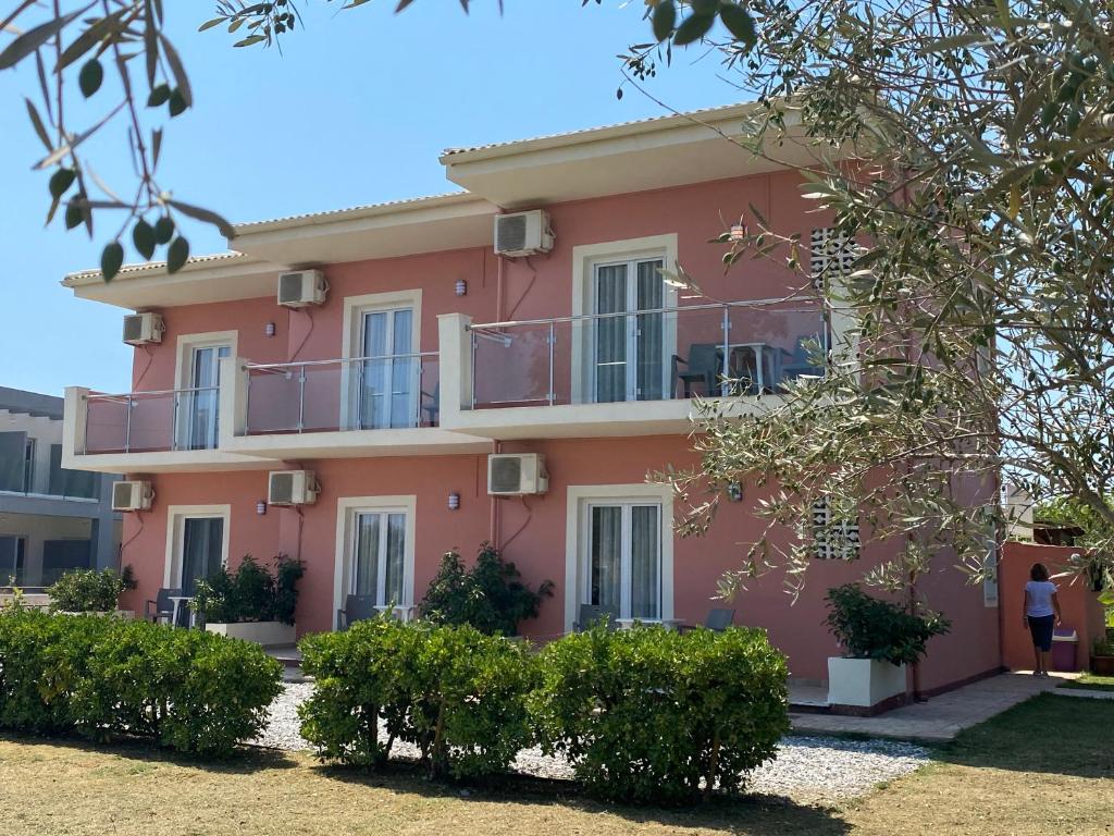 een roze huis met een vrouw ervoor bij Megali Beach Nikos in Sidari