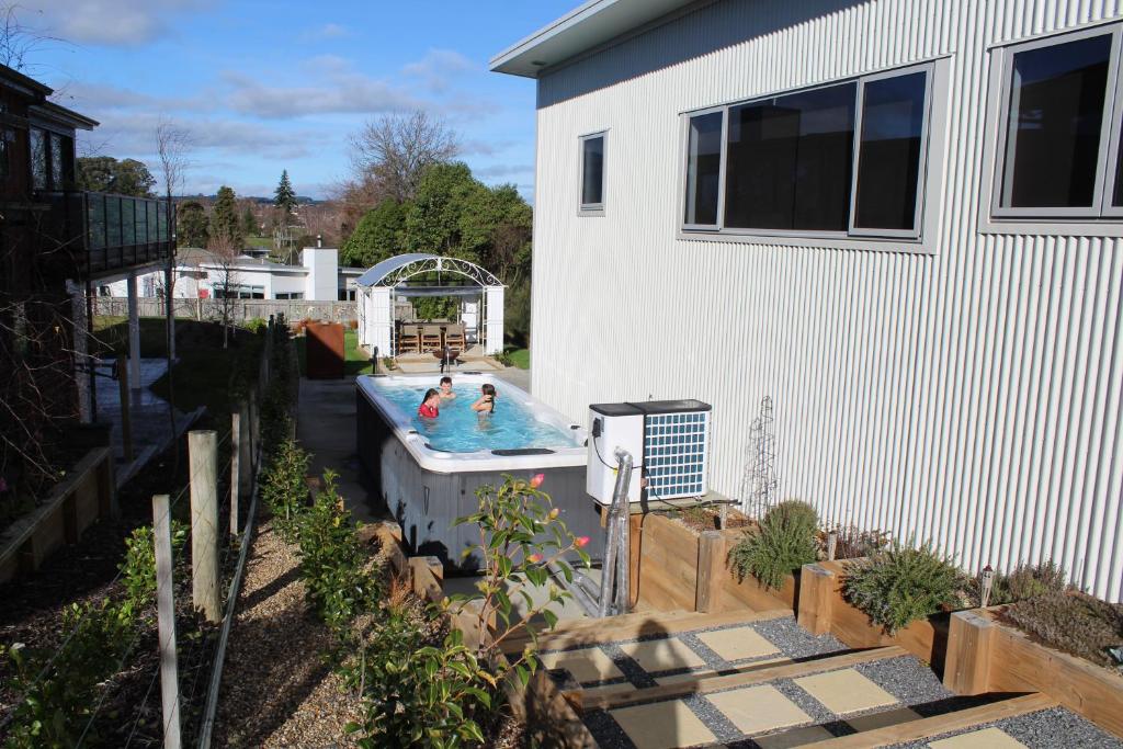 two people in a swimming pool next to a house at Luxury Retreat with Swim Spa in Taupo