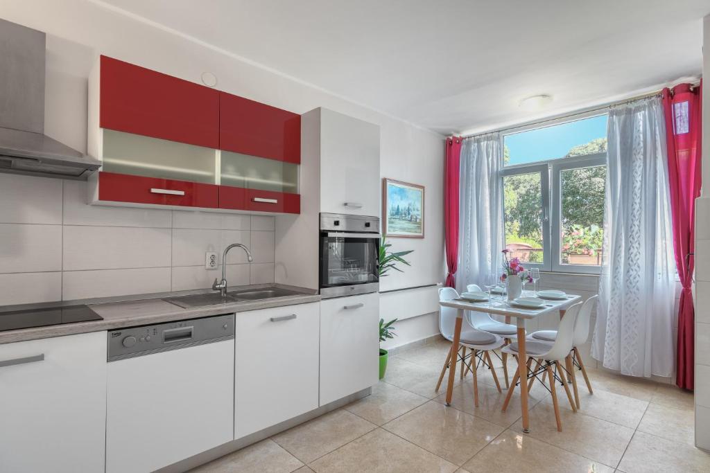 a kitchen with white cabinets and a table with chairs at M & M Apartment in Pula