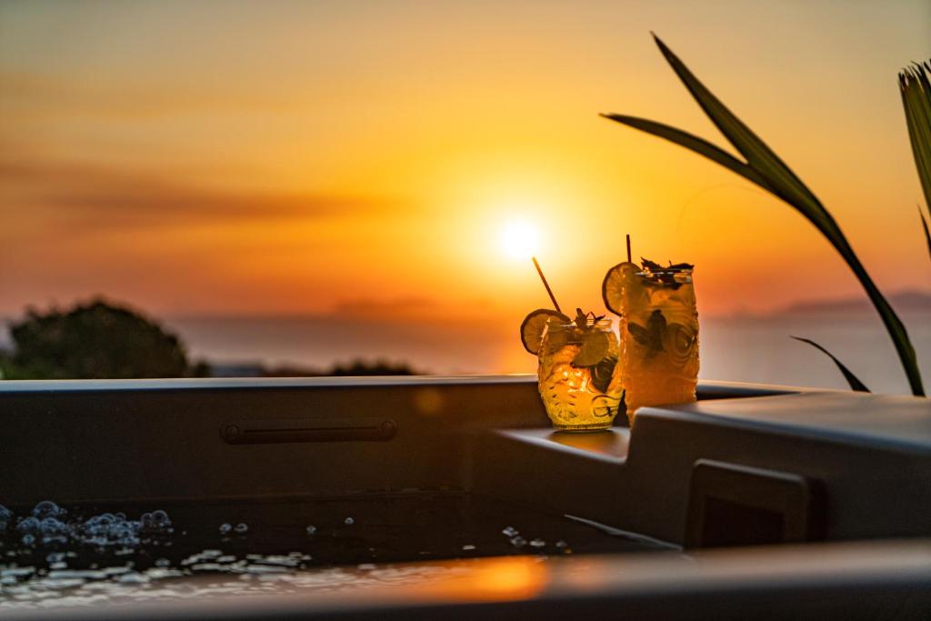 un paio di vasi su un tavolo con un tramonto sullo sfondo di Noelia Suites a Oia