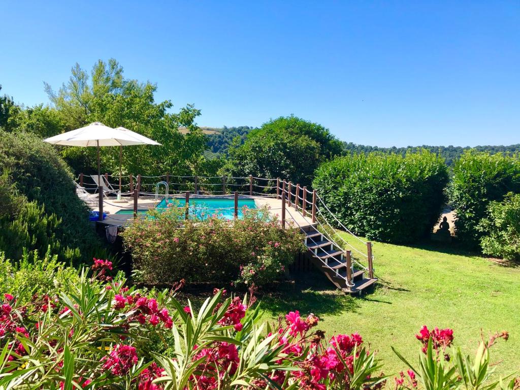 um jardim com piscina, guarda-sol e flores em Holiday home Sellanraa em Campagnano di Roma