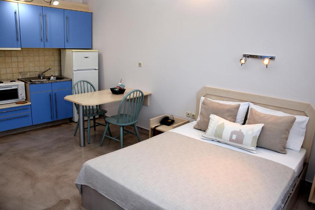 a bedroom with a bed and a kitchen with a table at Karystos Mare Apartments in Karistos
