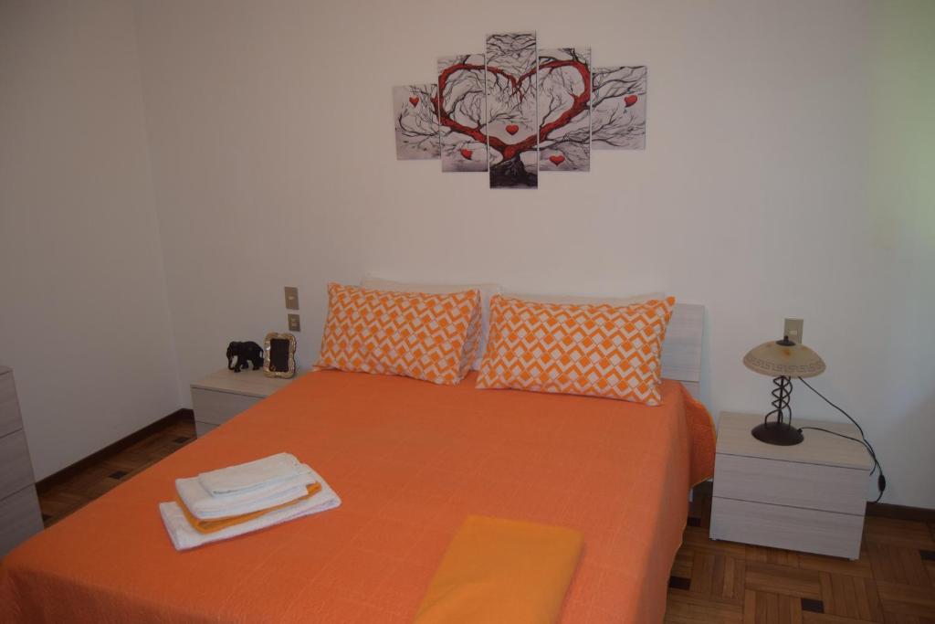 布斯托阿西齊奧的住宿－Al Salice tranquillità nel verde Via Amendola 24，一间卧室配有一张带橙色床单的床和墙上的时钟