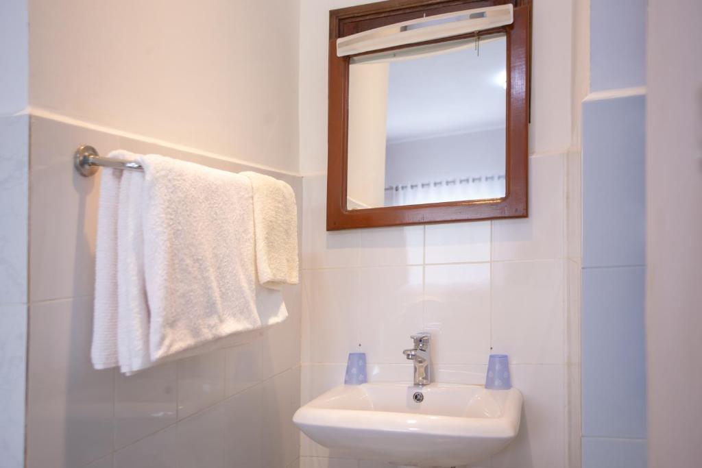 a bathroom with a sink and a mirror and towels at Andasibe Lemurs Lodge in Andasibe