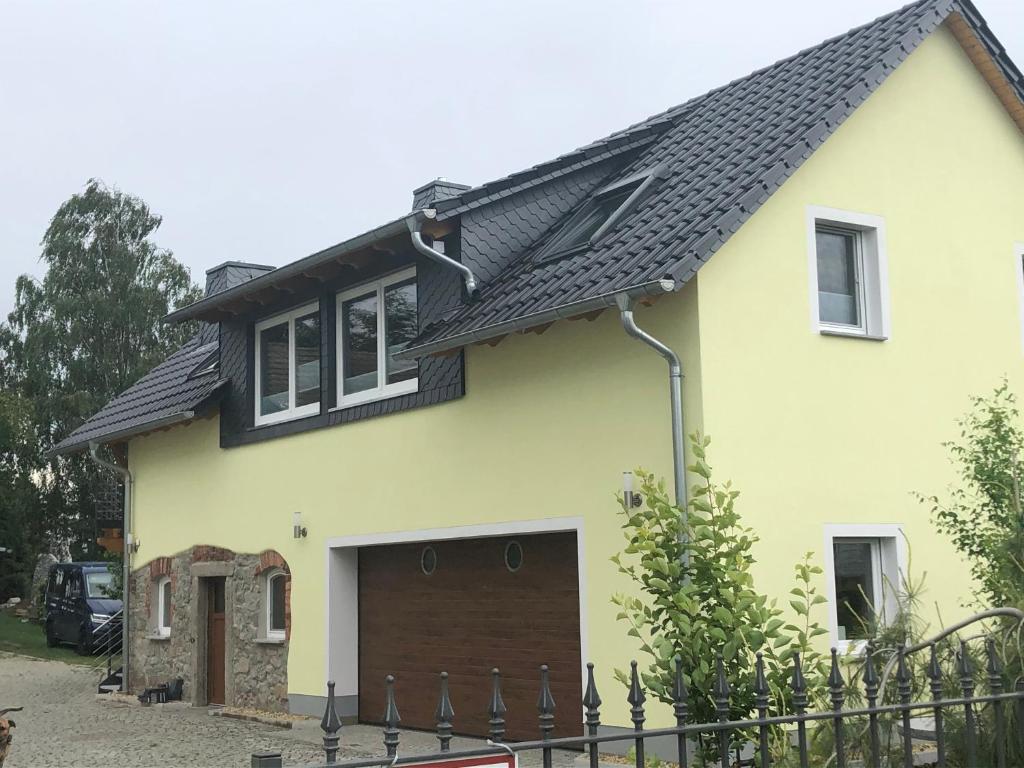 a yellow house with a black roof at Ferienwohnung „Zum Leuchtturm“ in Großdubrau