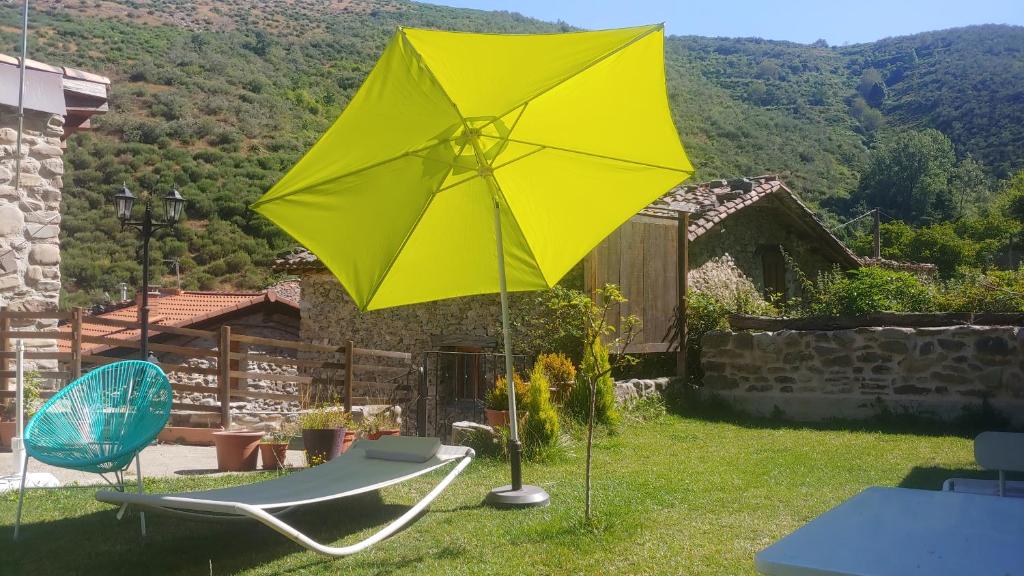 una sombrilla amarilla, una silla y una mesa en El Rincon De Zaldierna en Zaldierna