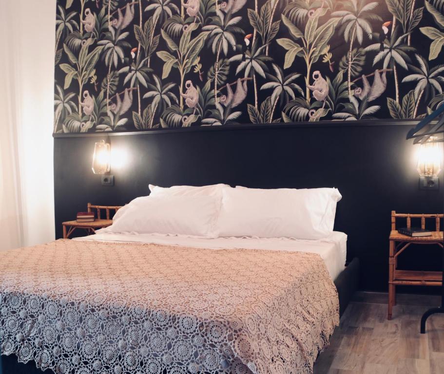 una camera da letto con un grande letto e carta da parati floreale di Le Stanze dello Scirocco a Catania